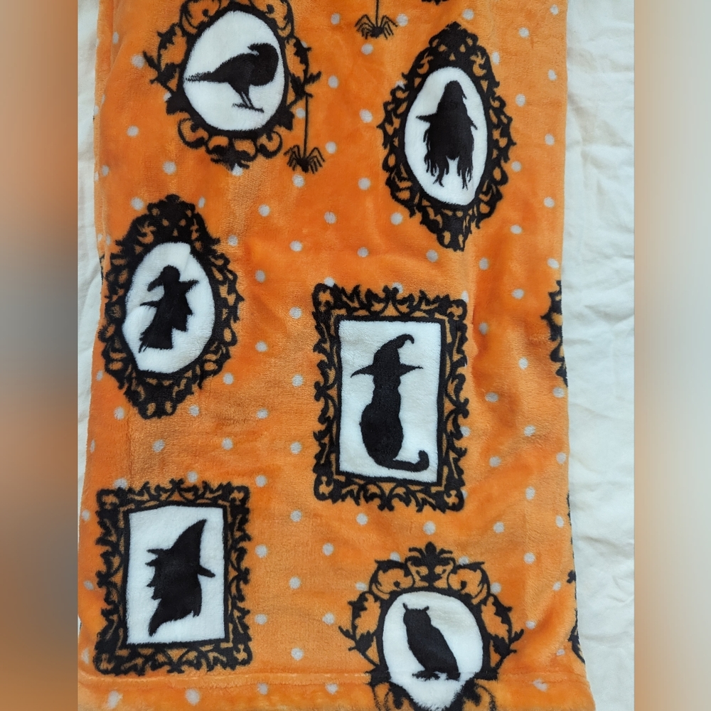 Orange plush throw blanket with black and white cameos all over